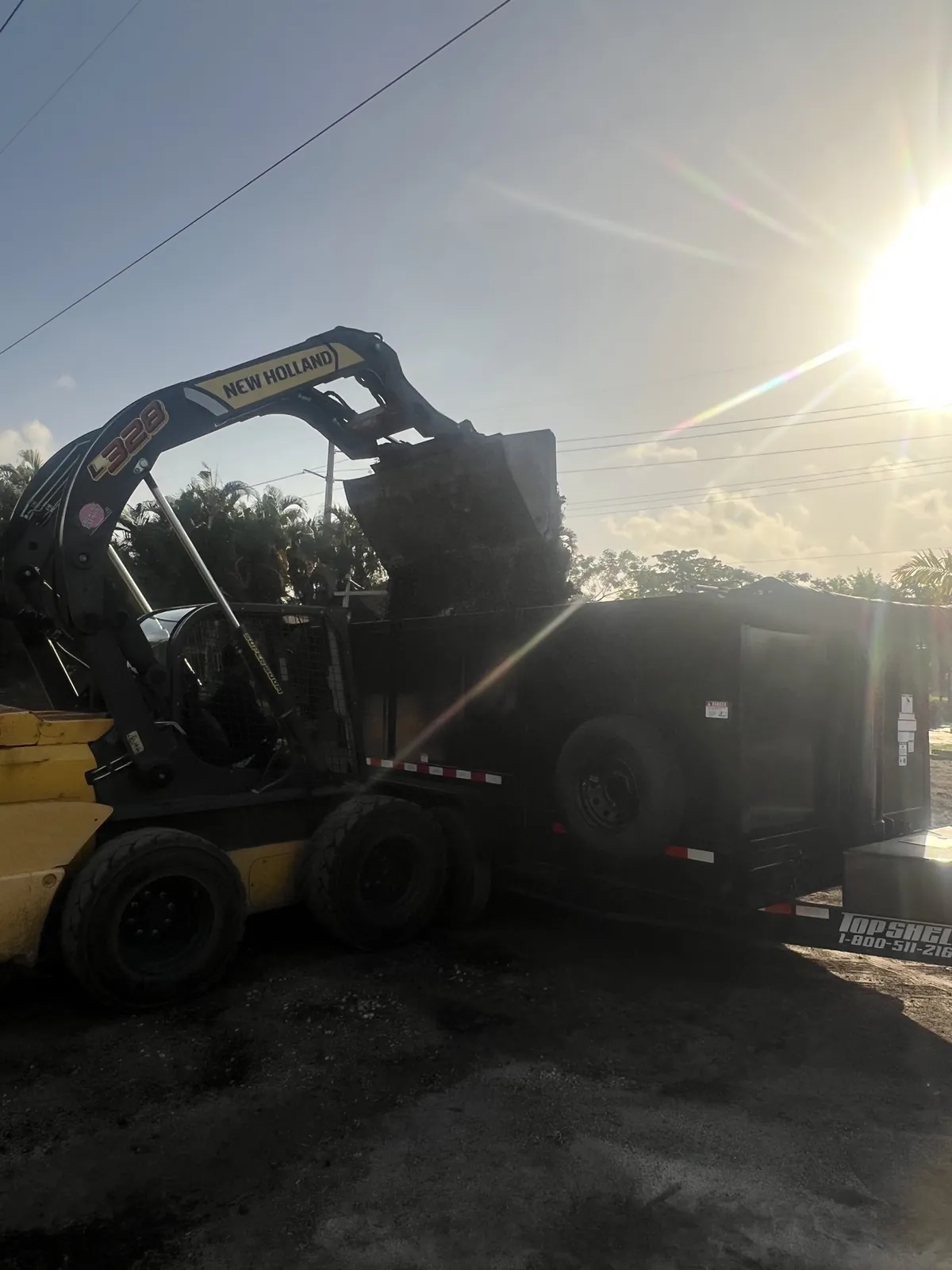 Skid steer loading demolition debris into a dump trailer in South Florida